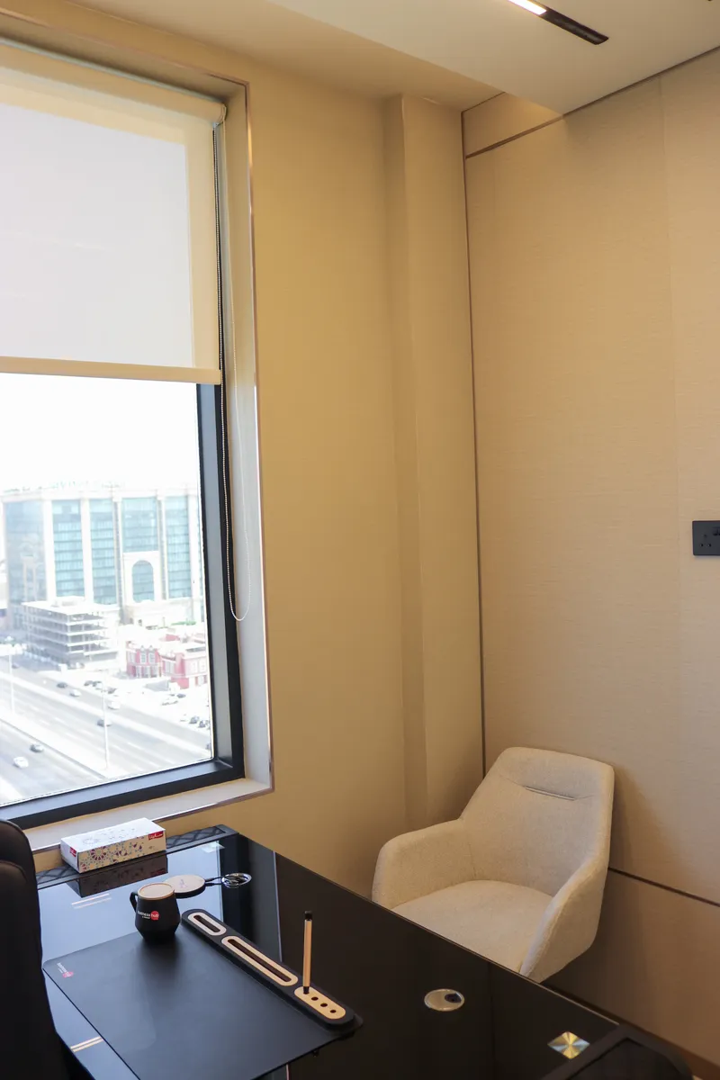 Office 57 · guest armchair beside a window with roller blind, desk in the foreground