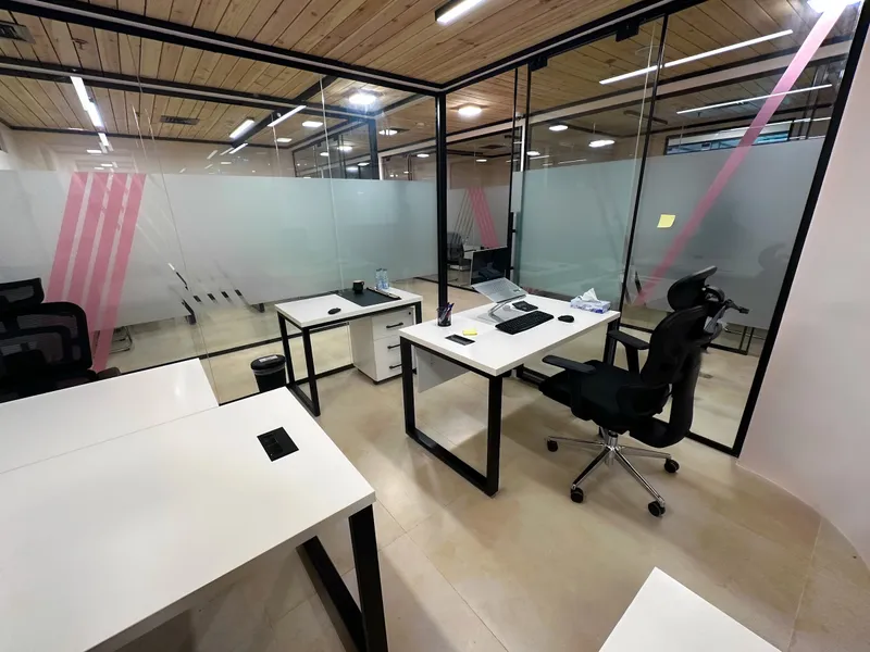 Office 28 · desks and a high-back mesh chair inside glass walls with frosted pink-striped panels