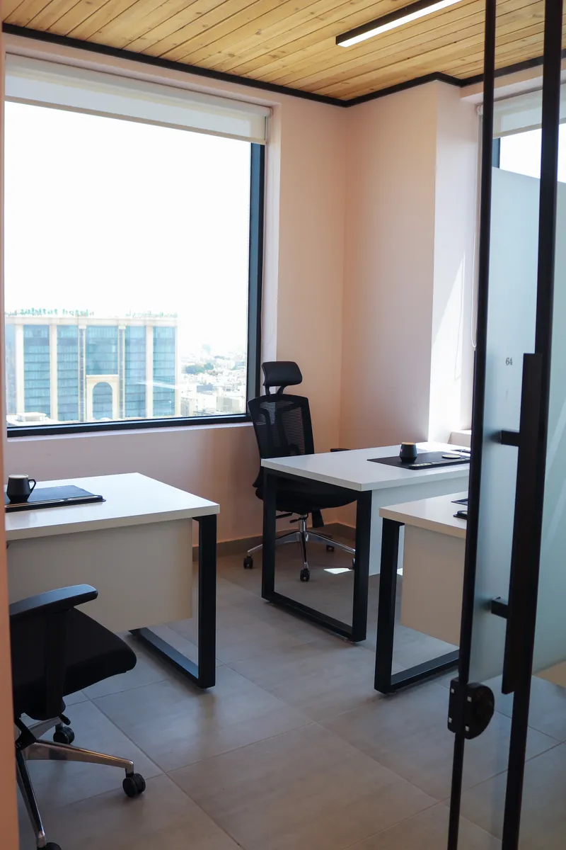 Office 64 · seen from the glass door: three desks, mesh chairs and a large window