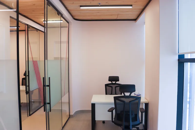 Office 70 · desk with two mesh chairs, glass sliding doors and a timber-slat ceiling