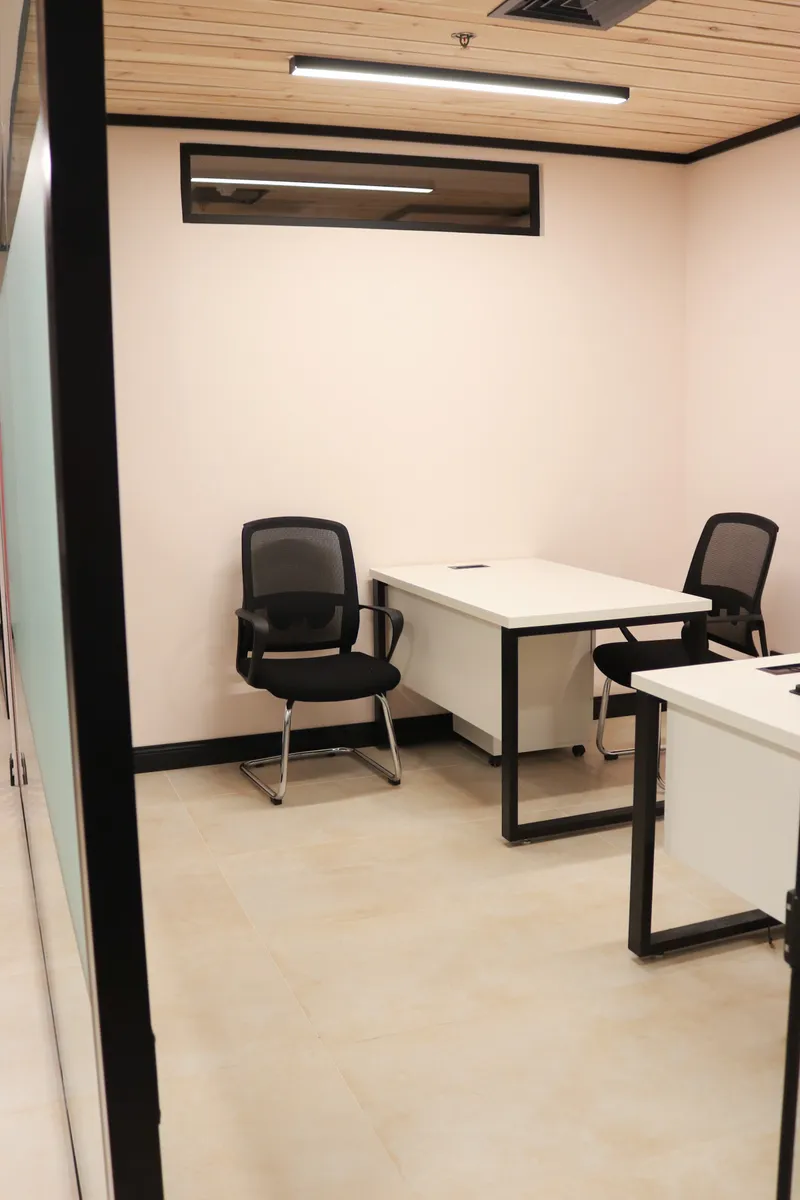 Office 23 · desk and two mesh visitor chairs under a wood-slat ceiling with a high strip window