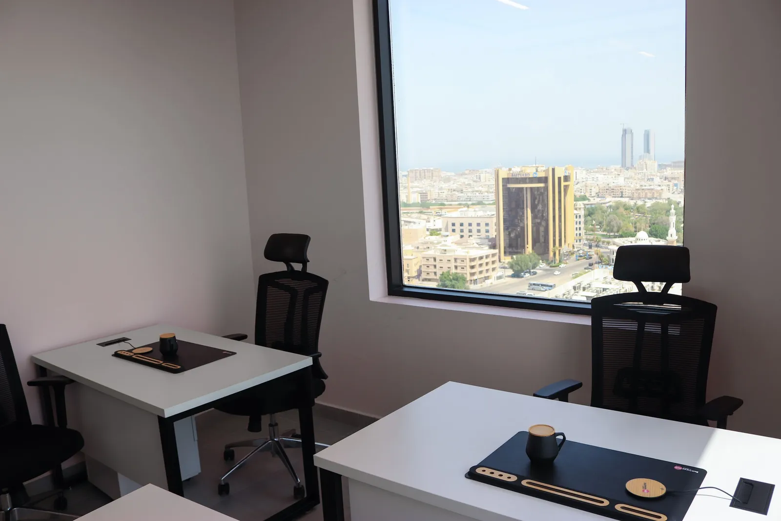 Office 64 · desks and mesh chairs beside a large window with a wide city view