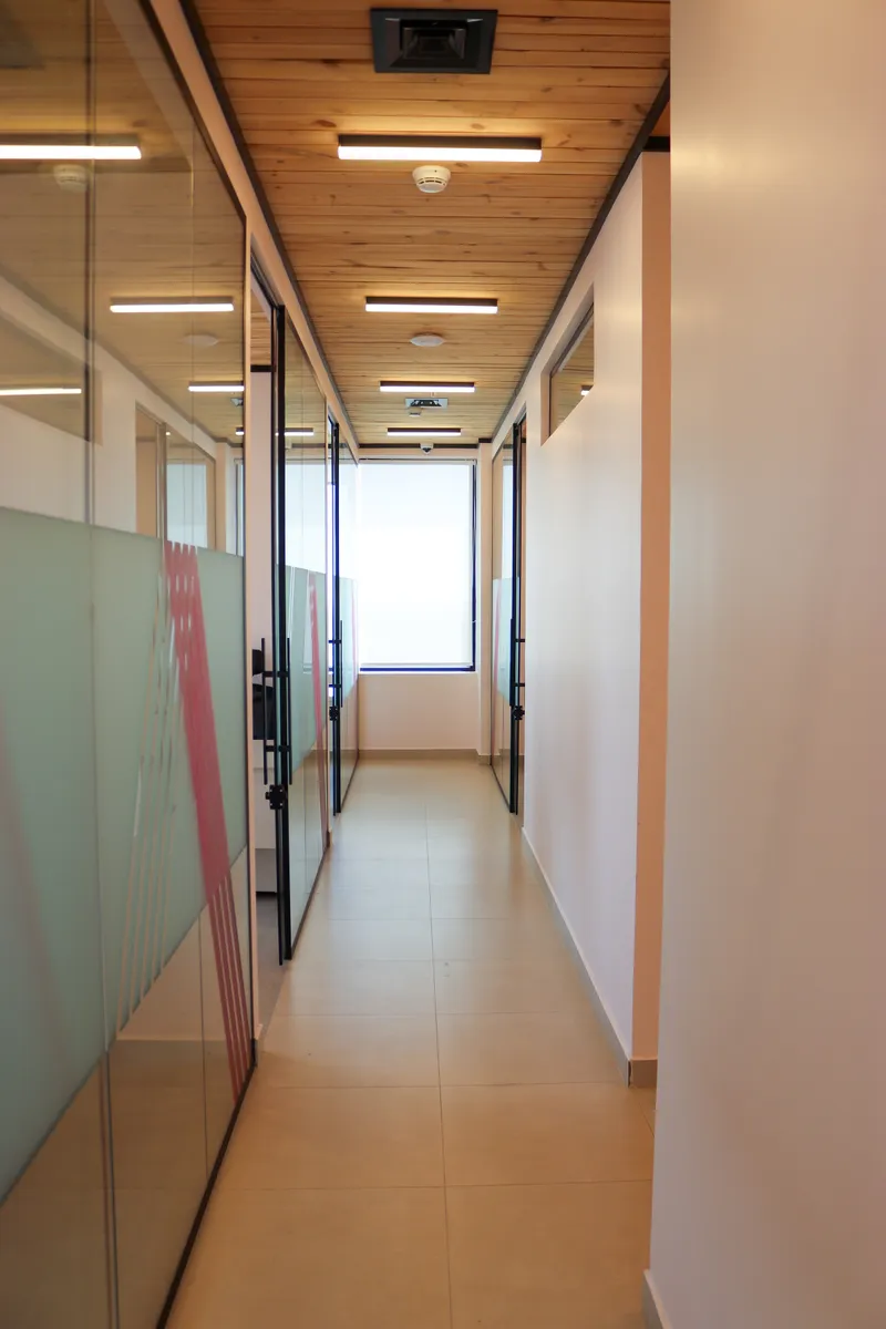 14th floor · side corridor between glass-fronted offices with frosted panels and pink stripes