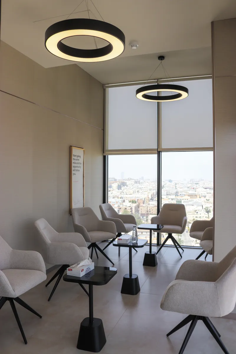 Catalyst · lounge armchairs and low tables under ring pendant lights, city view beyond