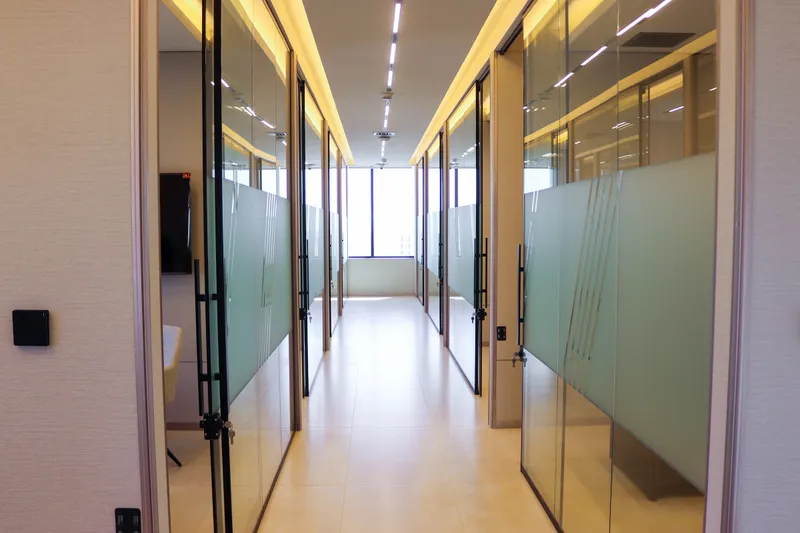 13th floor · corridor between glass-fronted offices with frosted bands and cove lighting