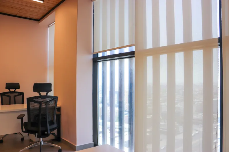 Office 70 · floor-to-ceiling windows with sheer roller blinds beside the desk area