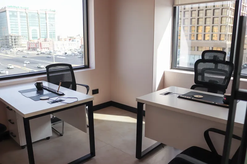 Office 36 · corner room with two windows over the street, two desks and mesh chairs