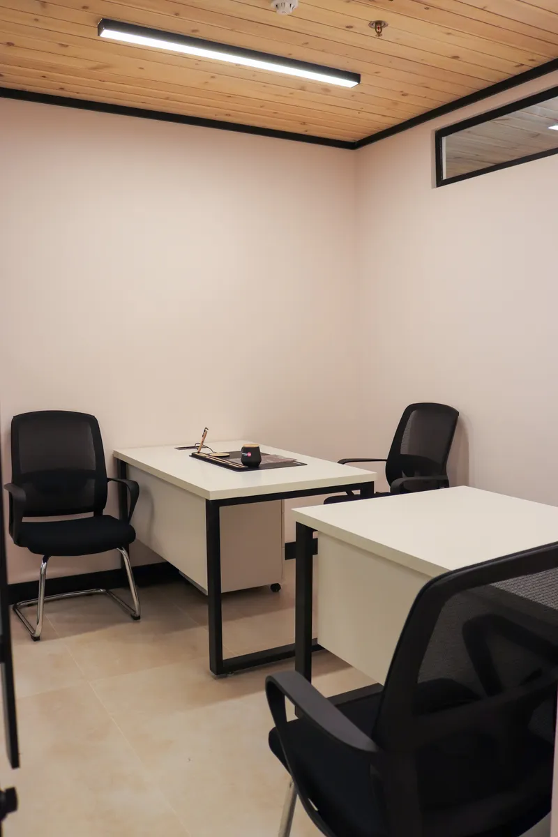 Office 2 · two white desks with black mesh chairs, a wooden ceiling and a high window strip