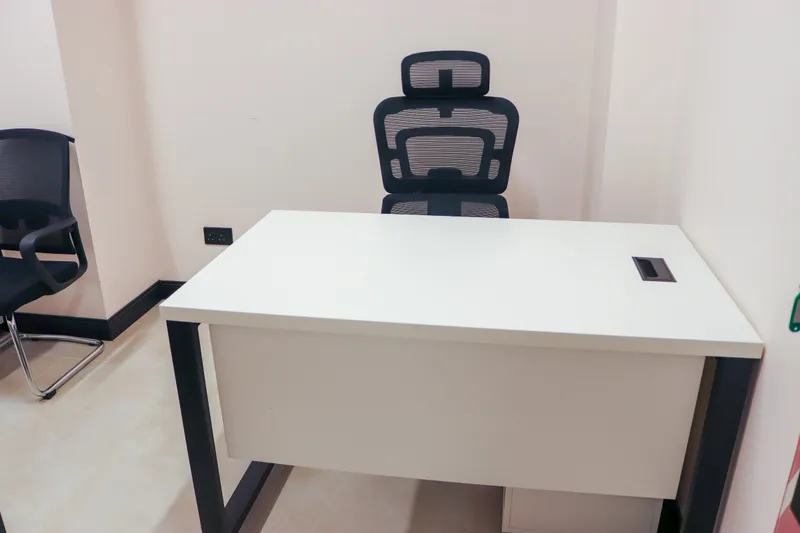 Office 19 · white desk with an ergonomic chair and a visitor chair against a plain wall