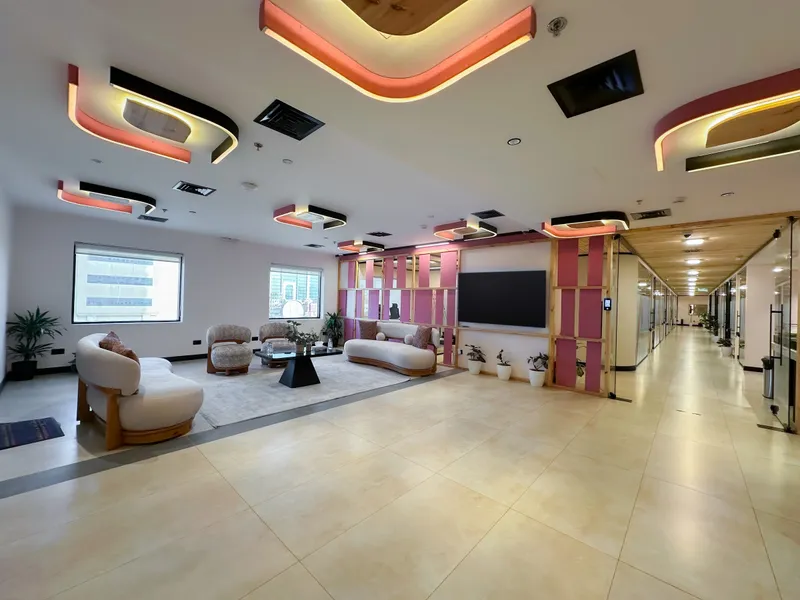 2nd floor · open lounge with curved sofas, armchairs and windows, the office corridor on the right