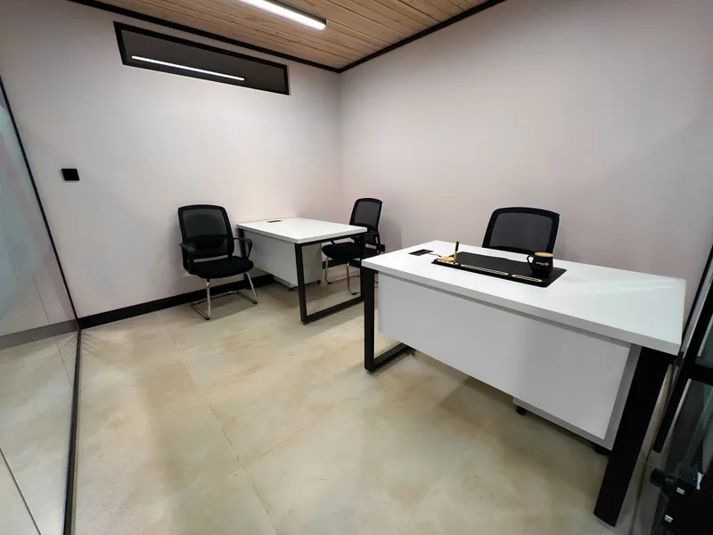 Office 23 · two white desks with mesh chairs and a desk mat under a wood-slat ceiling