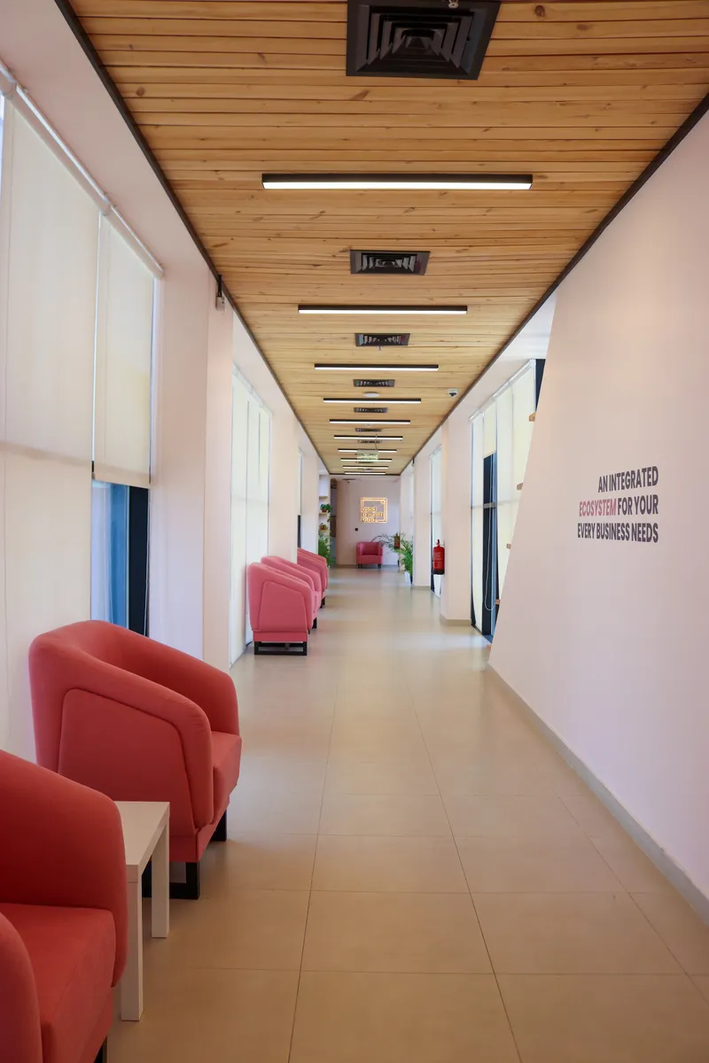 14th floor · corridor lounge with pink armchairs, a side table and a wall slogan under the timber ceiling