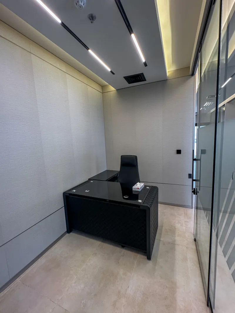 Office 60 · L-shaped desk and high-back chair, panelled walls and glass front