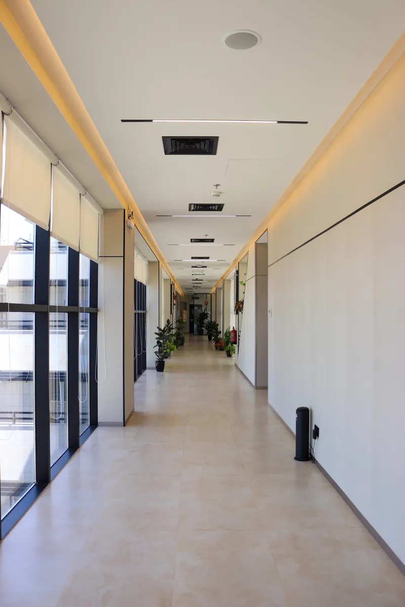 13th floor · long corridor with full-height windows on one side and warm cove lighting