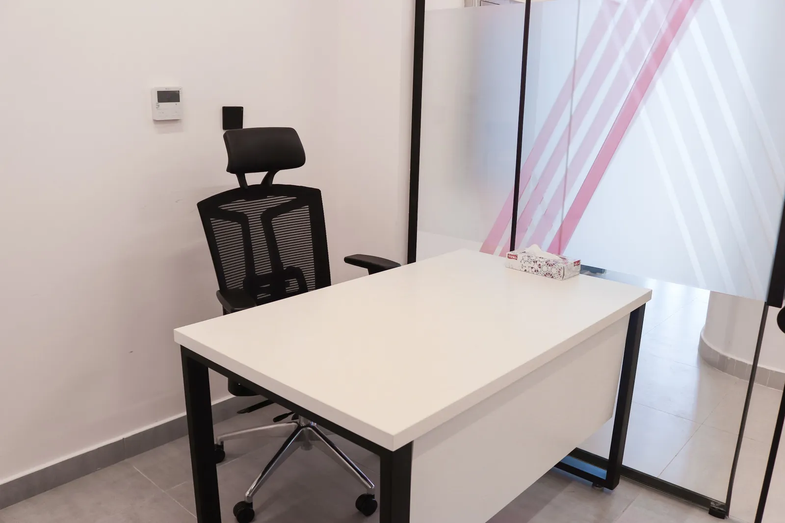 Office 69 · desk and high-back mesh chair beside a frosted glass front with pink stripes