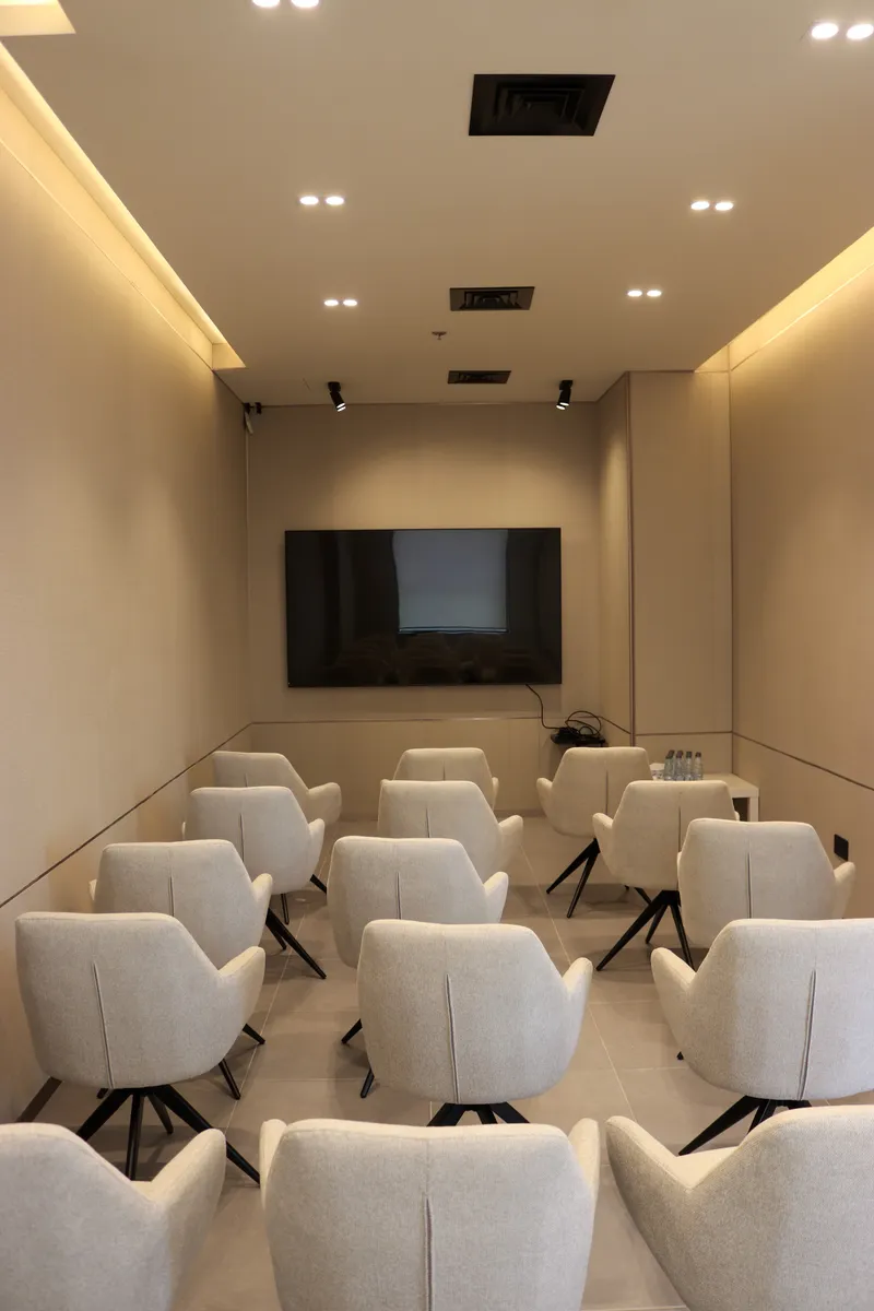 The Momentum Hall · theatre rows facing the wall screen under warm cove lighting