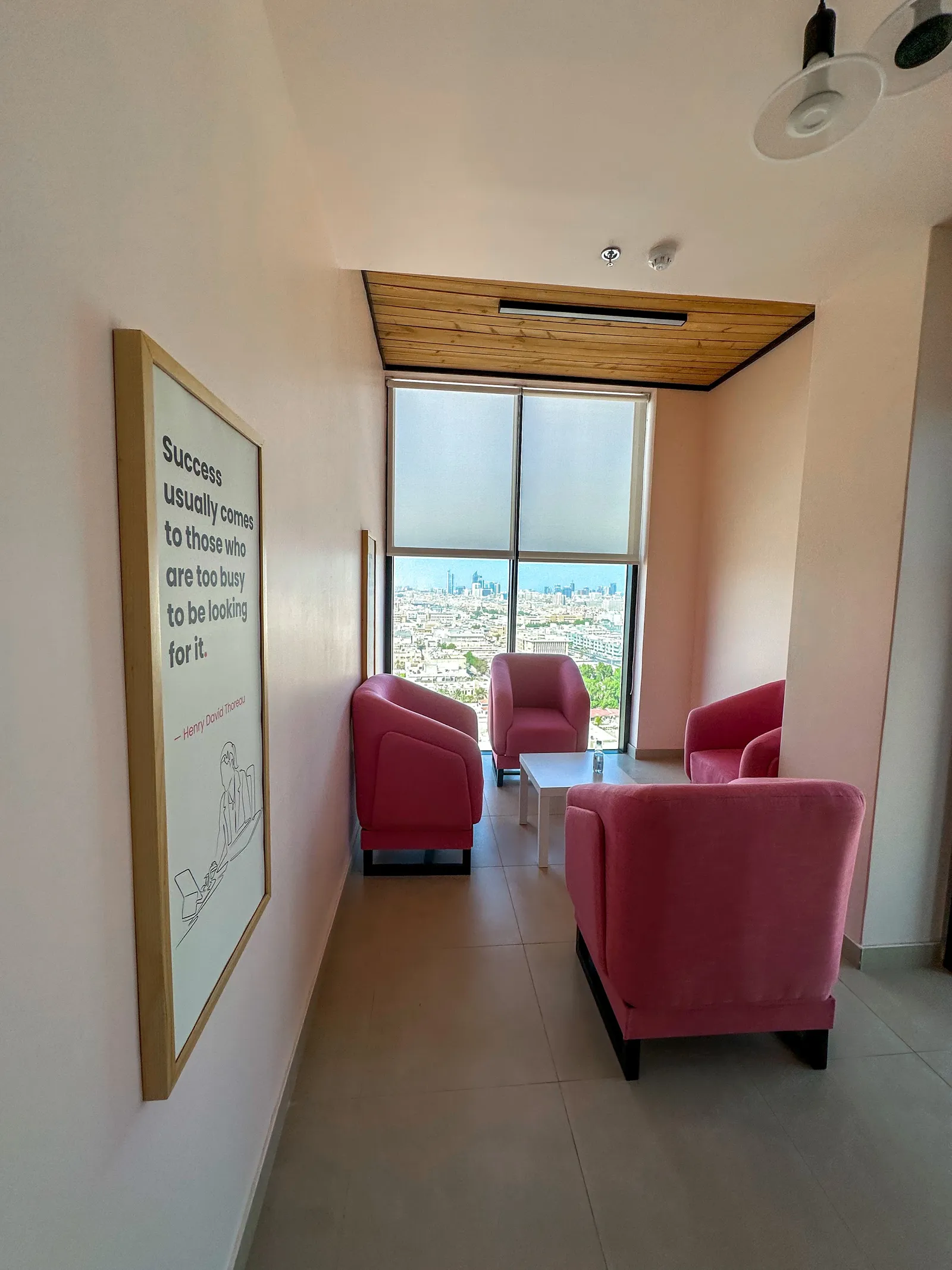 Sky Bridge · framed quote poster and pink armchairs round a low table at the window