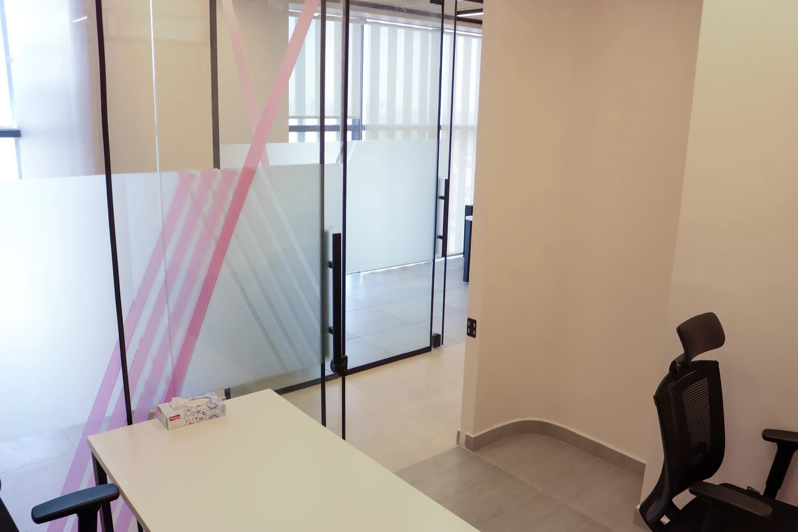 Office 69 · view past the desk to the frosted glass door and the corridor windows