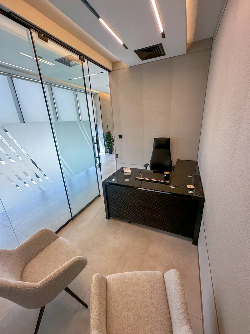 Office 63 · desk and guest armchairs beside a glass partition with a frosted band