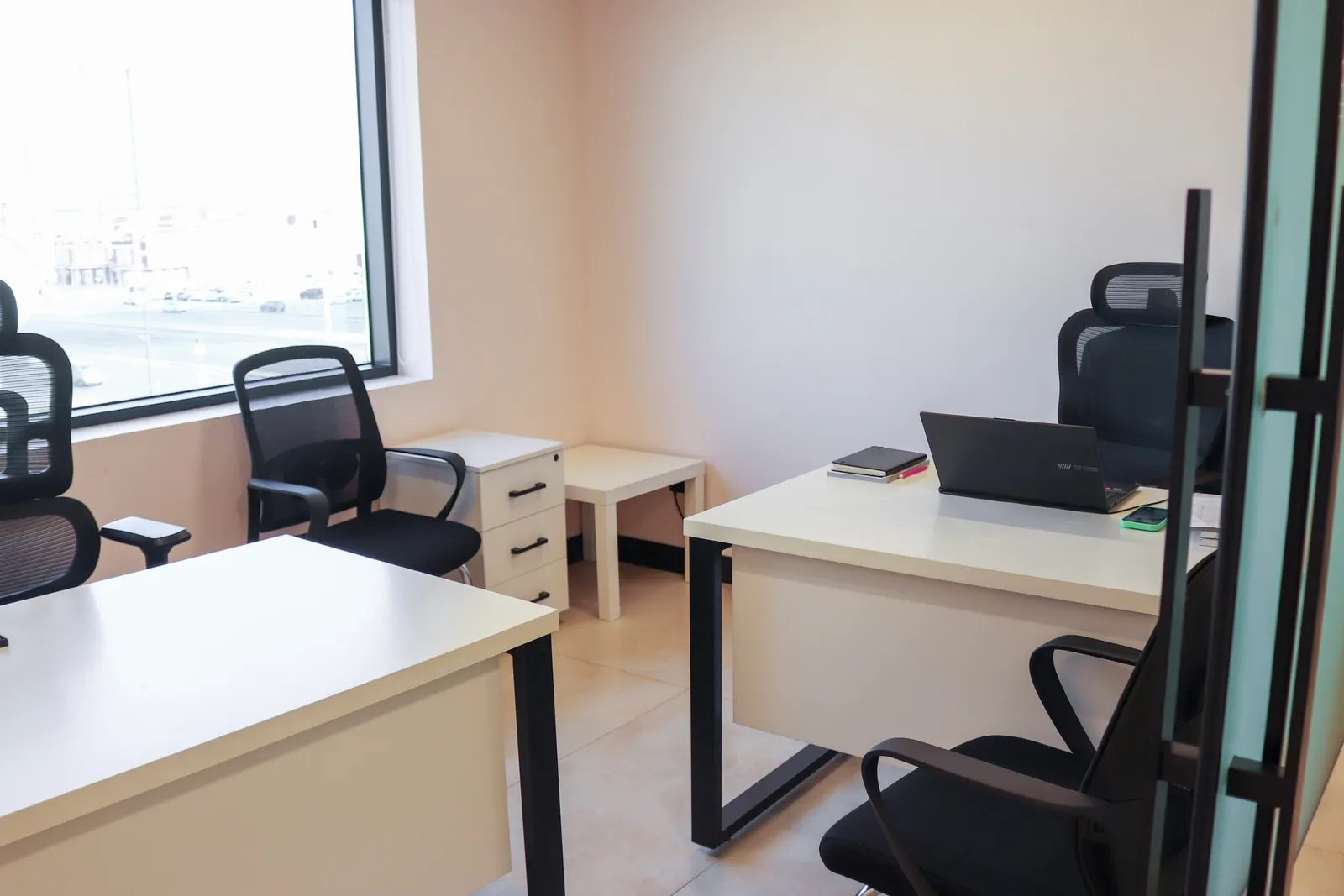 Office 43 · two desks with mesh chairs, a drawer unit and a side table beside a window