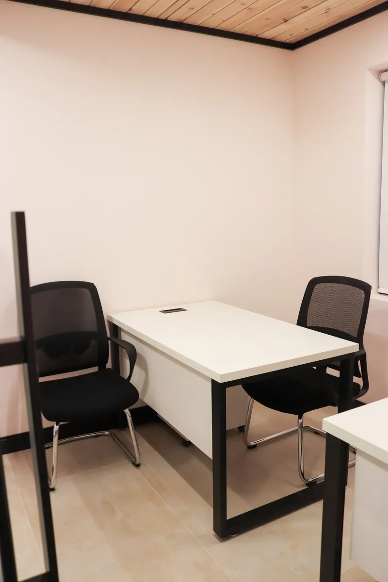 Office 30 · white desk between two mesh visitor chairs against light pink walls