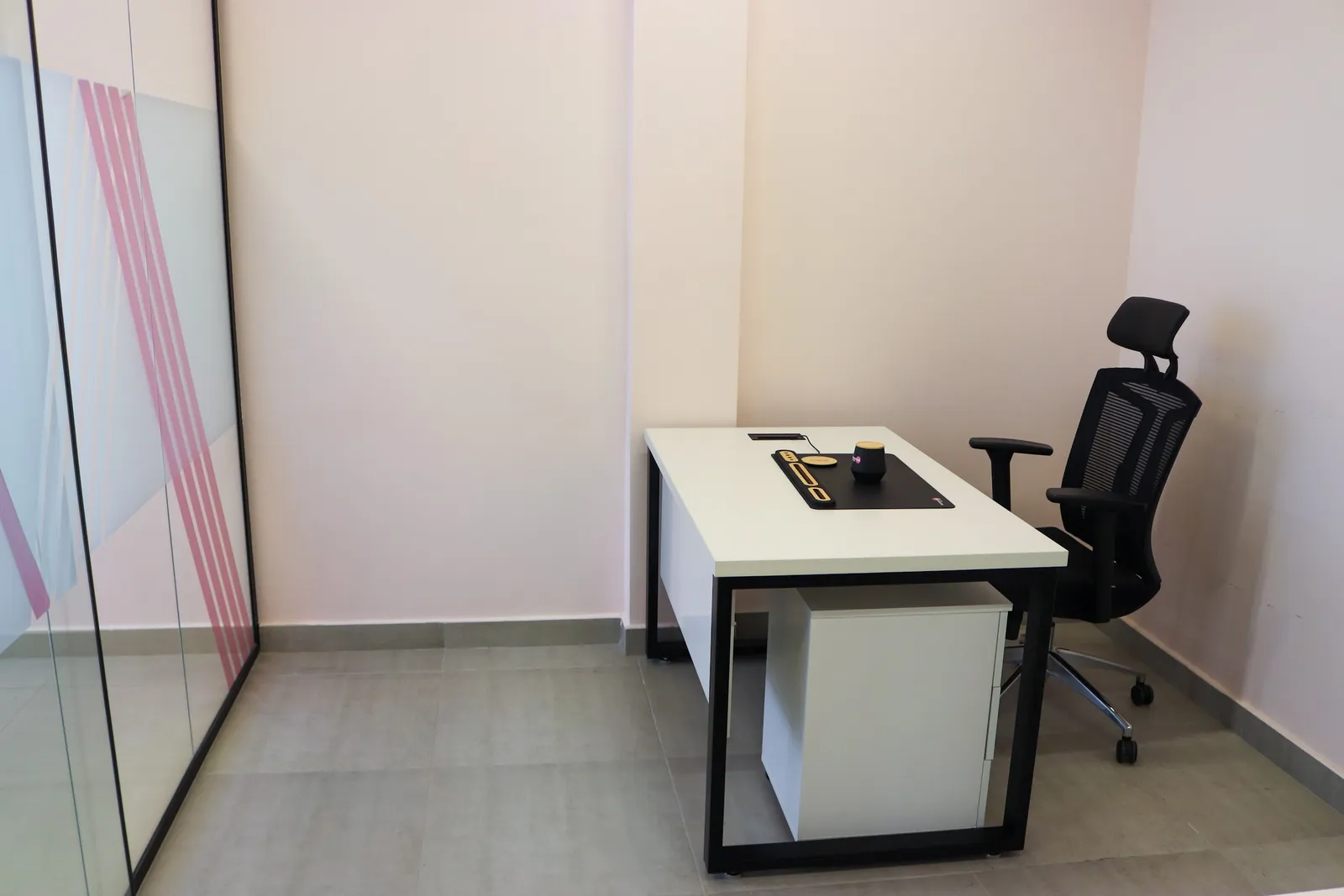 Office 68 · desk, mesh chair and mobile pedestal beside a frosted glass front with pink stripes