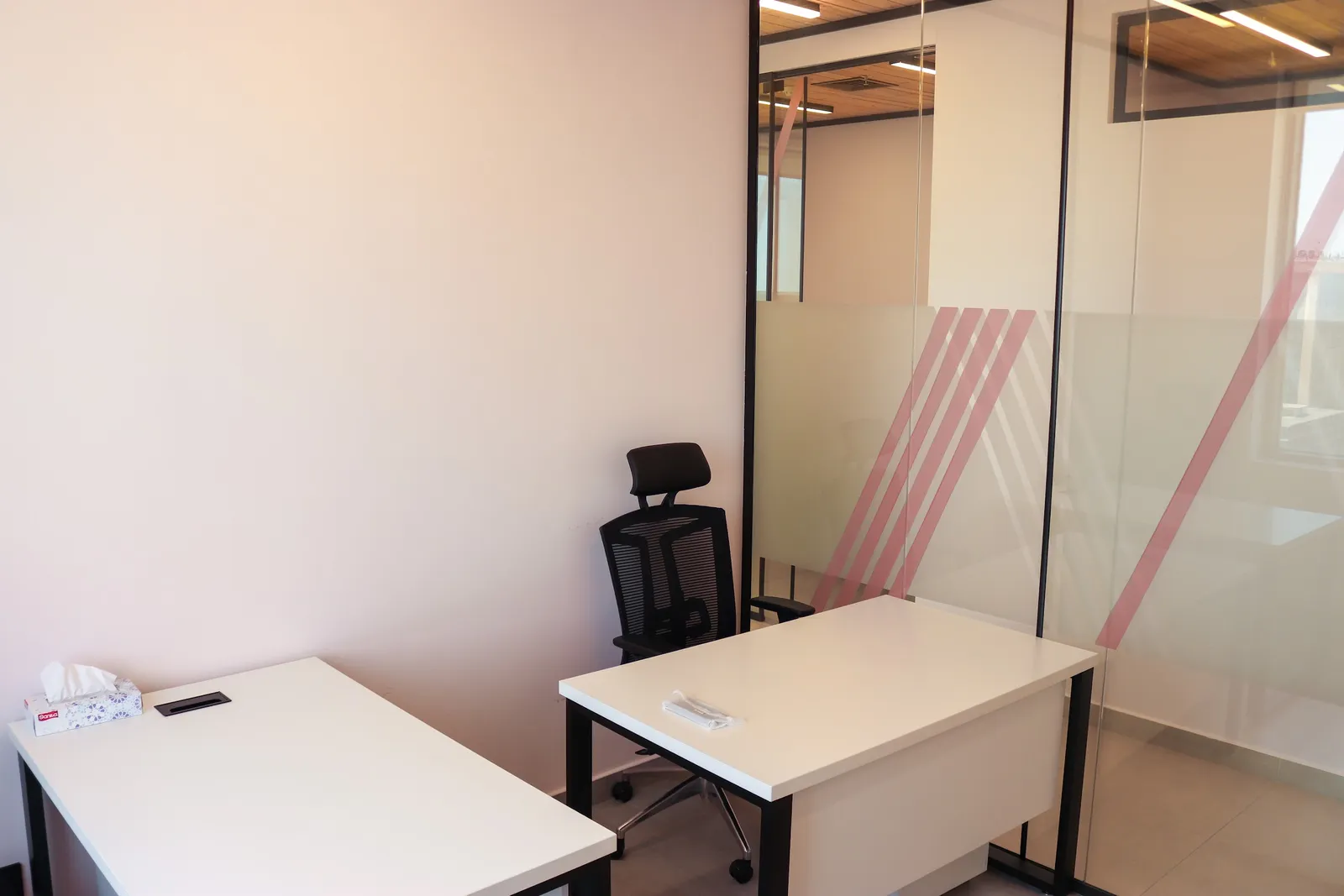Office 65 · two desks and a task chair along the glass wall with pink-striped frosting
