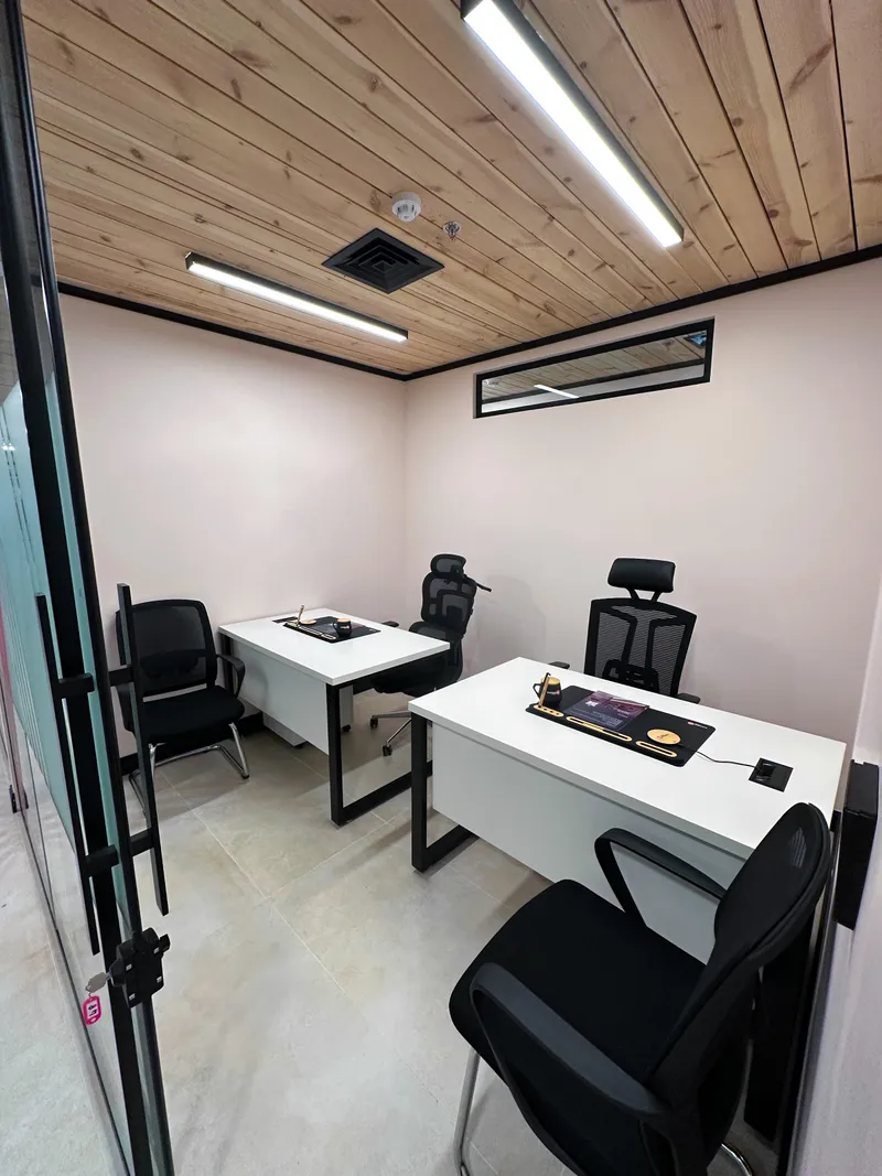 Growth Office · two desks with mesh and visitor chairs under a wooden ceiling, seen from the open glass door