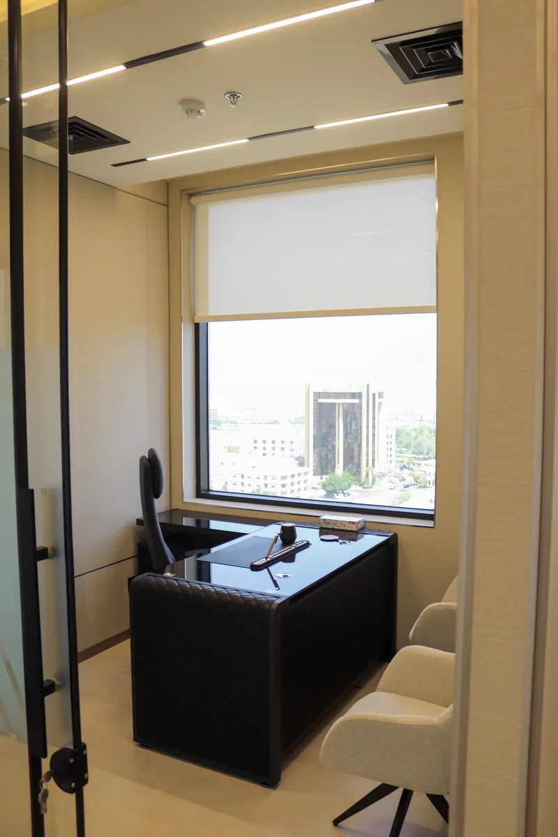 Office 57 · L-shaped desk, high-back chair, two guest armchairs and a city-view window