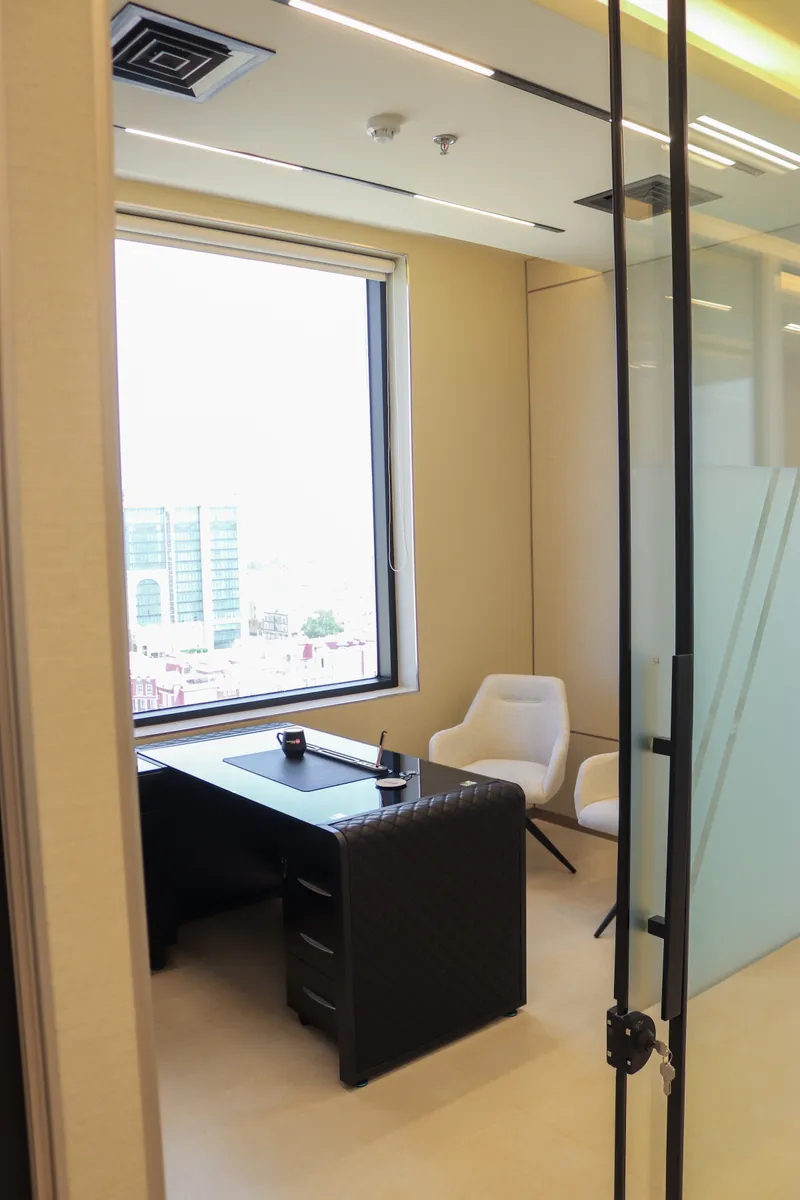 Office 54 · desk, two guest armchairs and a city-view window seen through the glass door