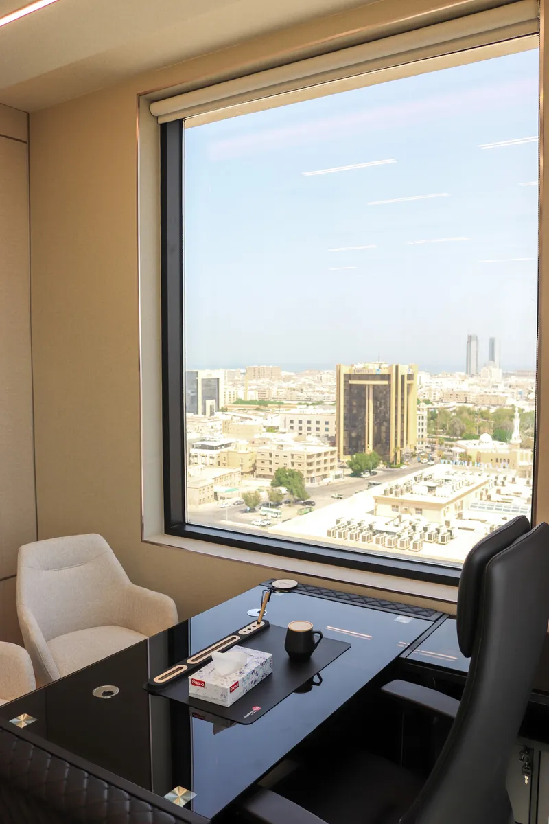 Office 53 · desk and guest armchair beside a large window over the city