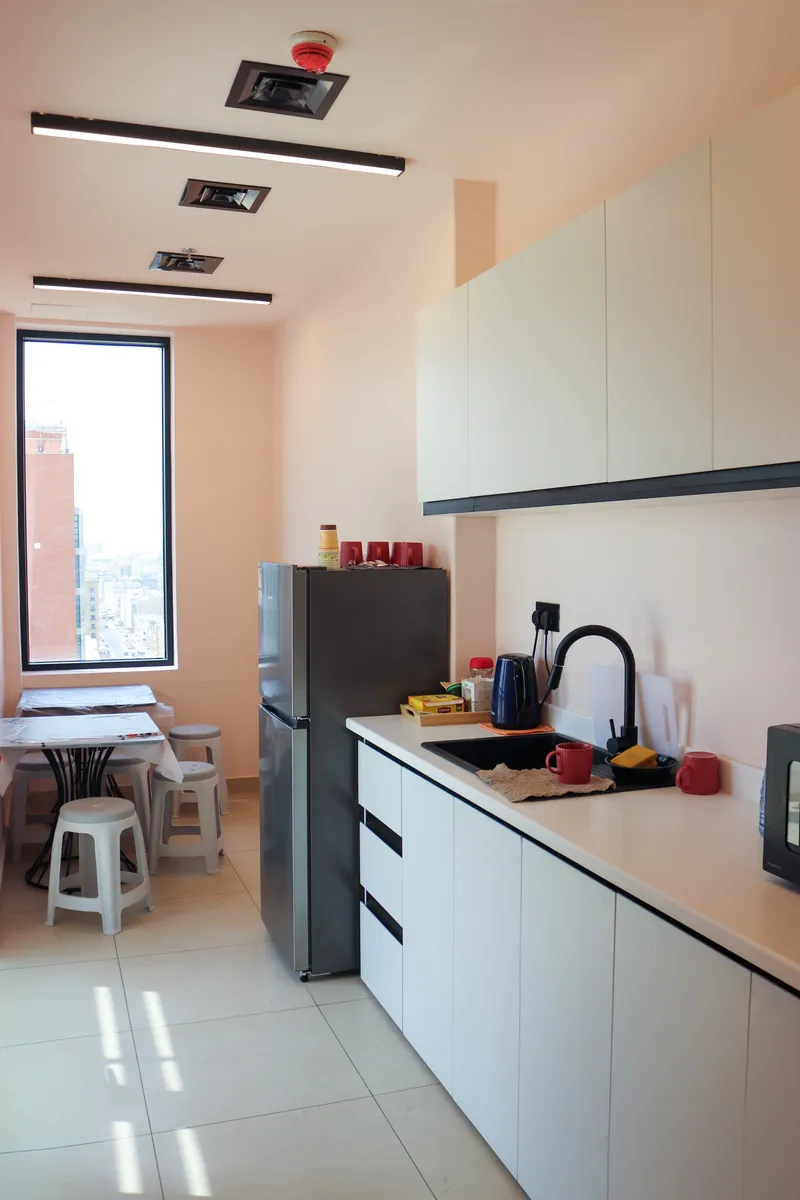 14th floor · pantry with white cabinets, fridge, sink and kettle, and a small table corner by the window