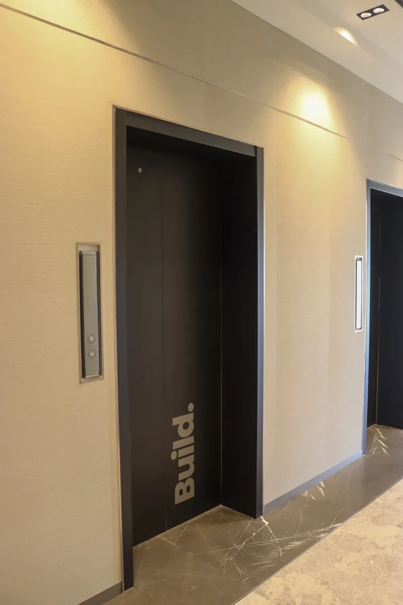 13th floor · dark lift doors, one lettered "Build.", on a marble floor