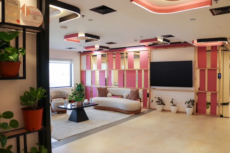 2nd floor · waiting lounge with a curved sofa, armchairs and a wall screen on a pink slatted partition