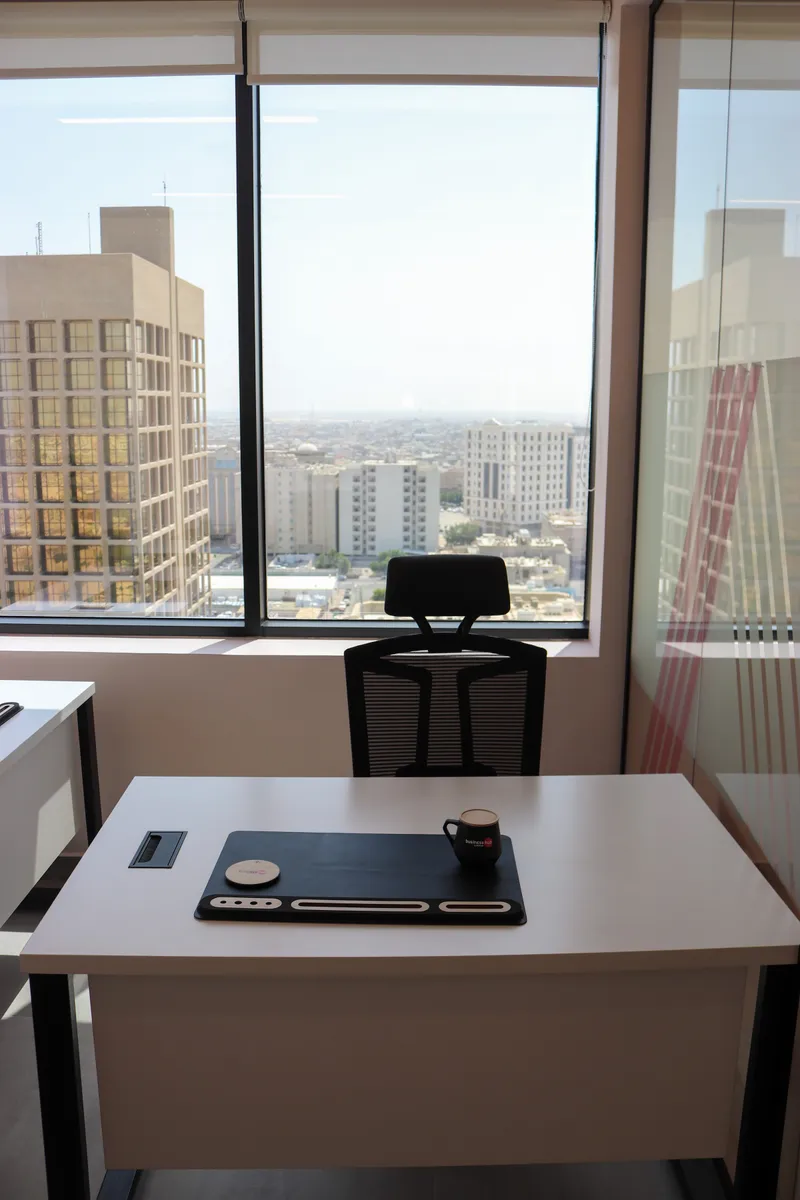 Office 64 · desk and mesh chair facing a wide window with city views