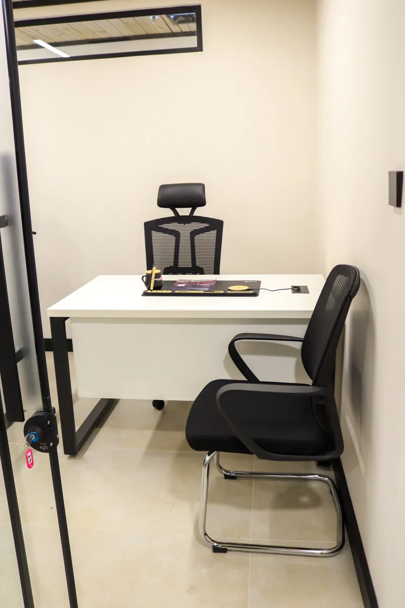 Growth Office · white desk with a high-back chair and a visitor chair, seen through the glass door