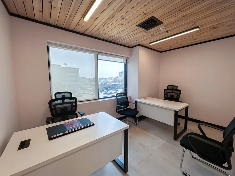 Office 33 · two white desks and four chairs in The Collective, under a wooden ceiling by a street window