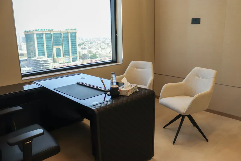 Office 55 · desk, two guest armchairs and a large window over the city
