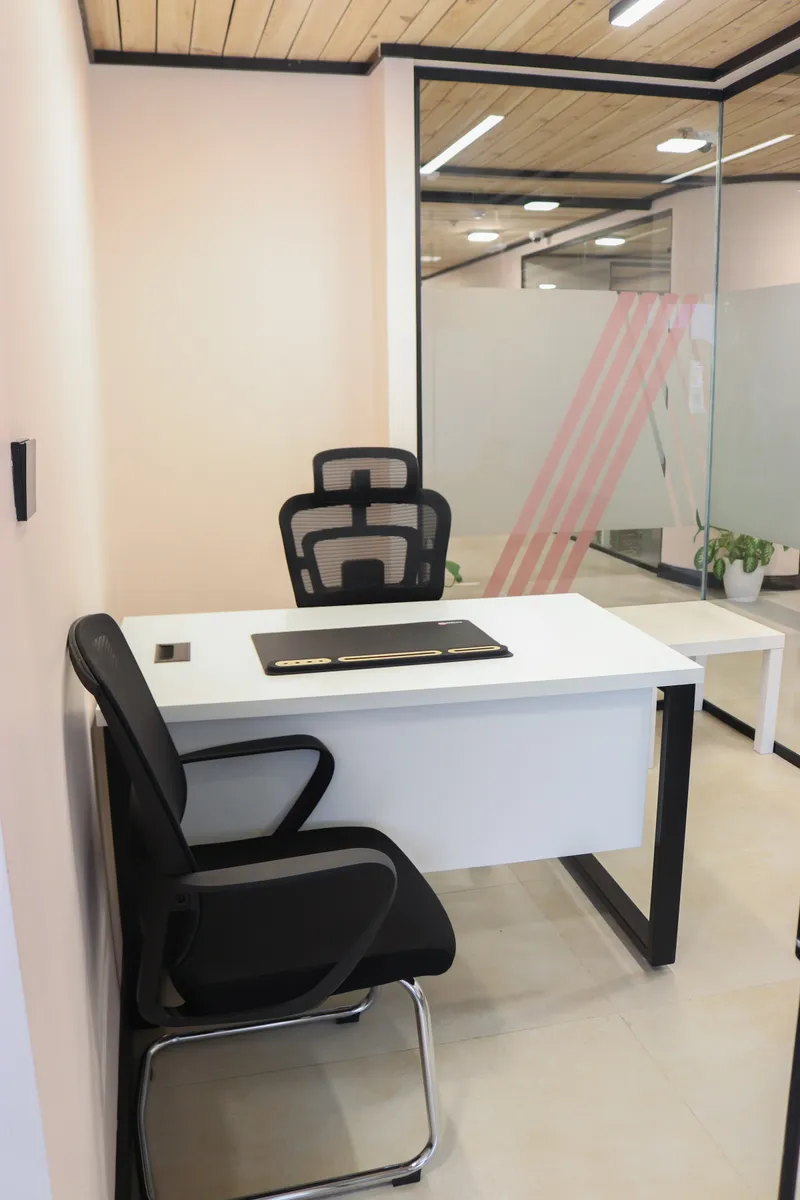 Office 34 · desk with a mesh chair and a guest chair beside a glass wall with pink stripes