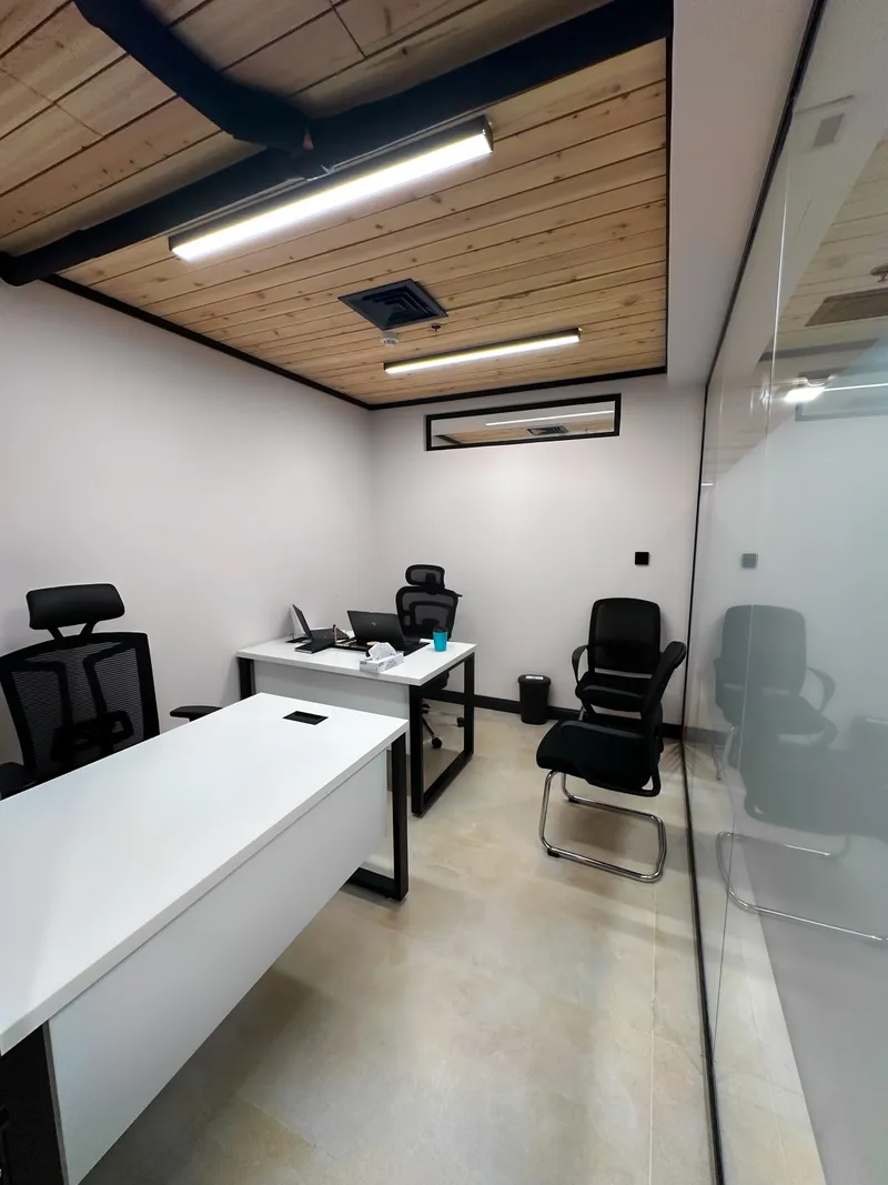 Growth Office · two white desks, mesh chairs and a wood-slat ceiling beside a glass wall