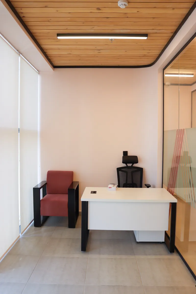 Office 70 · desk, high-back chair and red guest armchair beside window blinds
