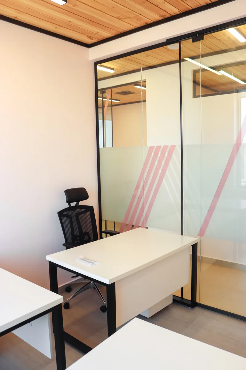 Office 65 · desk and task chair by the frosted glass wall under a timber ceiling