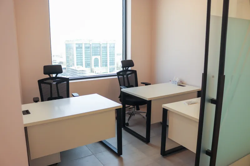Office 65 · three white desks and mesh task chairs by a large window over the city