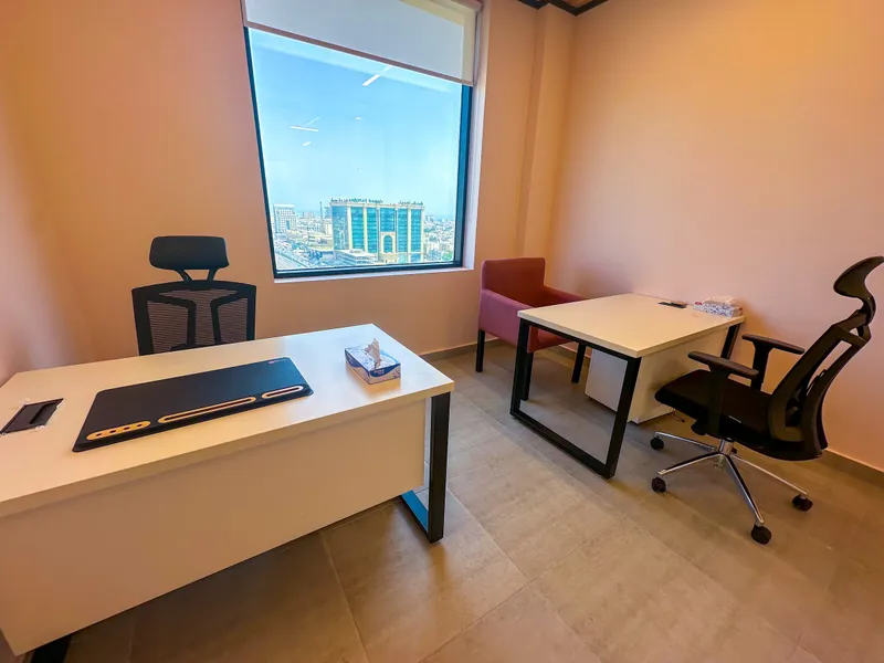 Office 66 · wide view of both desks, a pink armchair and a window over the city