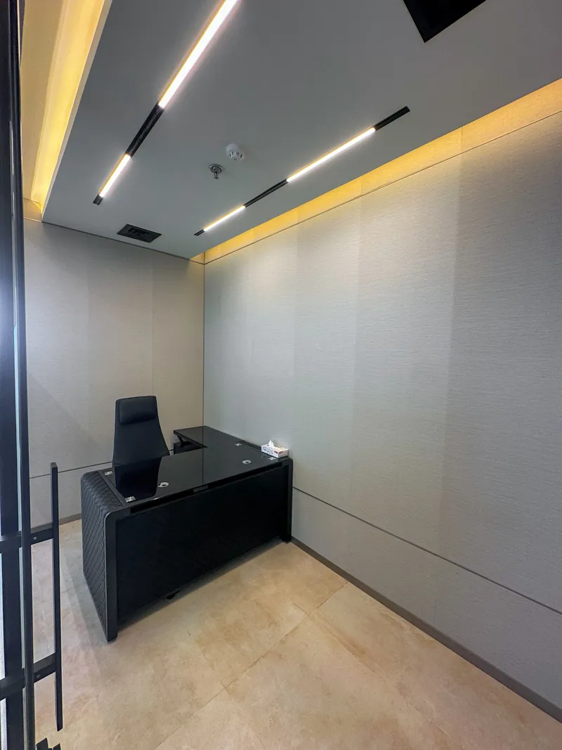 Office 59 · L-shaped desk and chair under linear ceiling lights and cove lighting