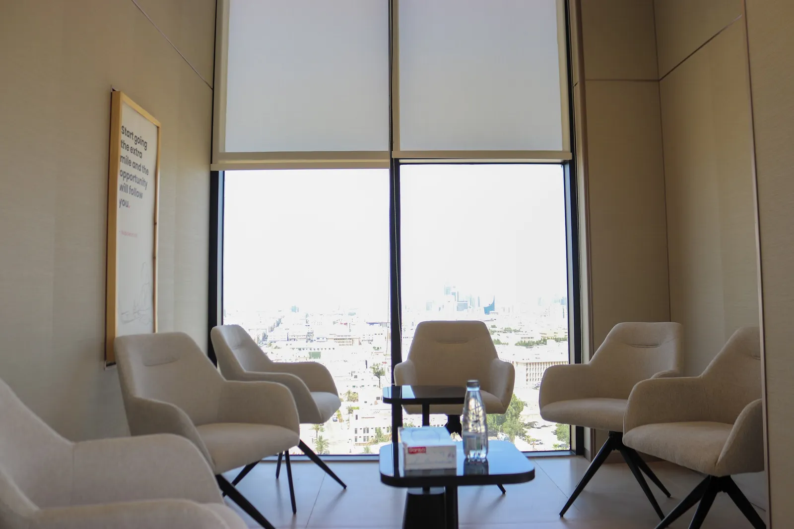 Catalyst · armchairs around a low table at the window, city view beyond