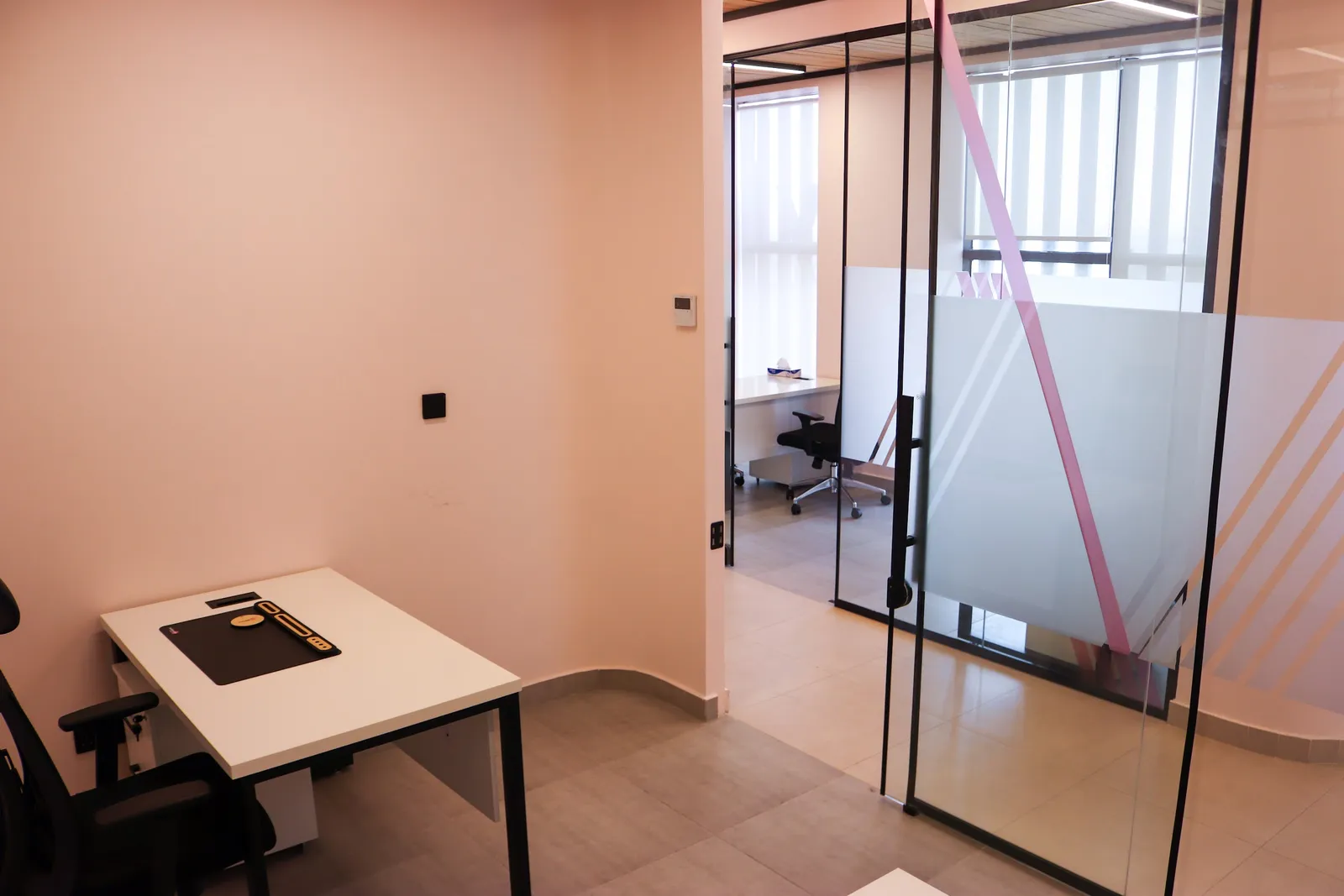 Office 68 · desk beside the glass door, with the neighbouring office visible beyond