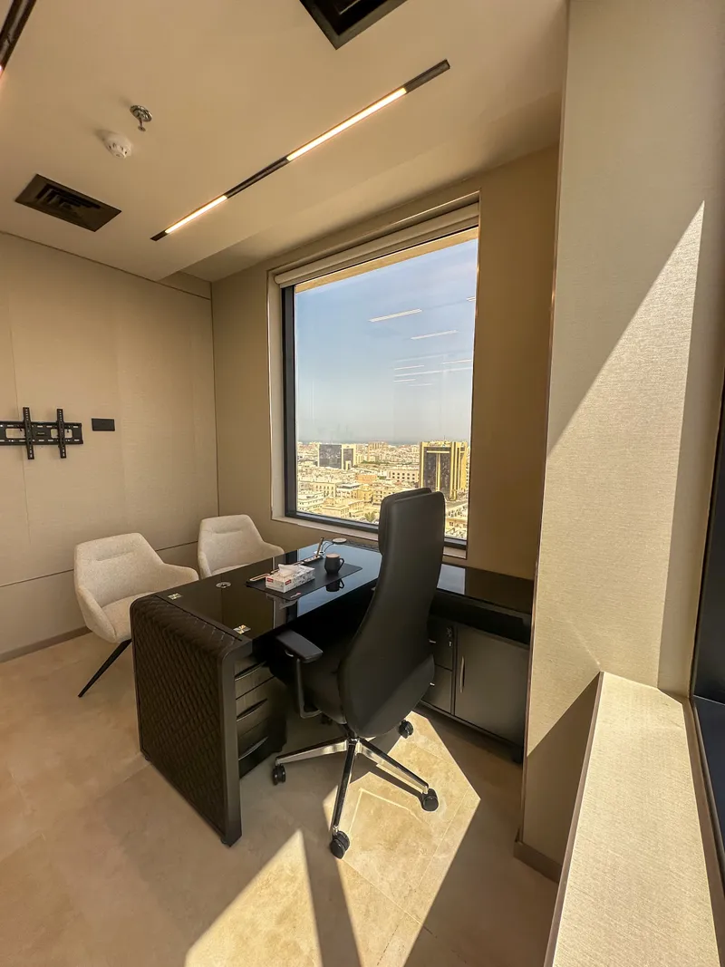 Office 53 · desk with storage return, two guest armchairs and a window over the city