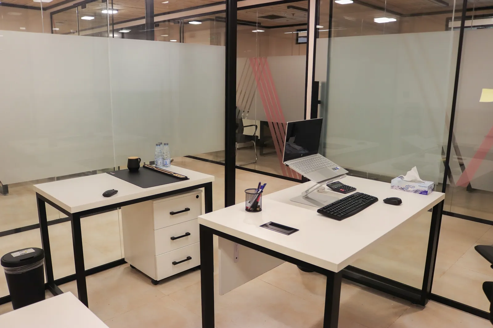 Office 28 · two desks and a drawer unit inside frosted glass walls with pink stripes