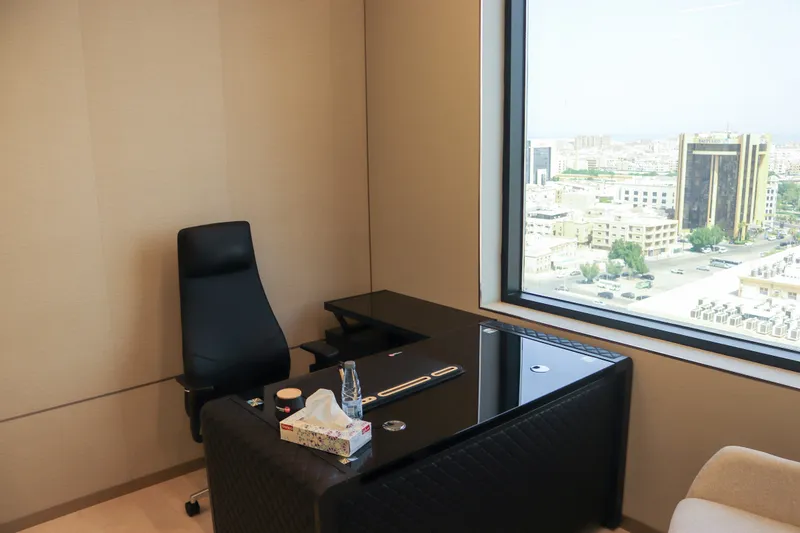 Office 55 · L-shaped desk and executive chair beside a city-view window